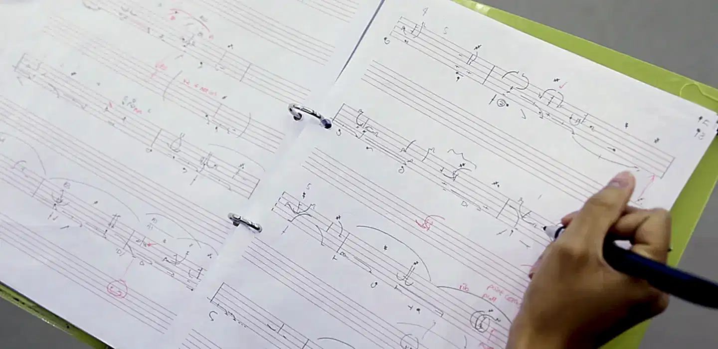 benesh | Royal Academy of Dance Open notebook with benesh notation and a student writing in the sheet